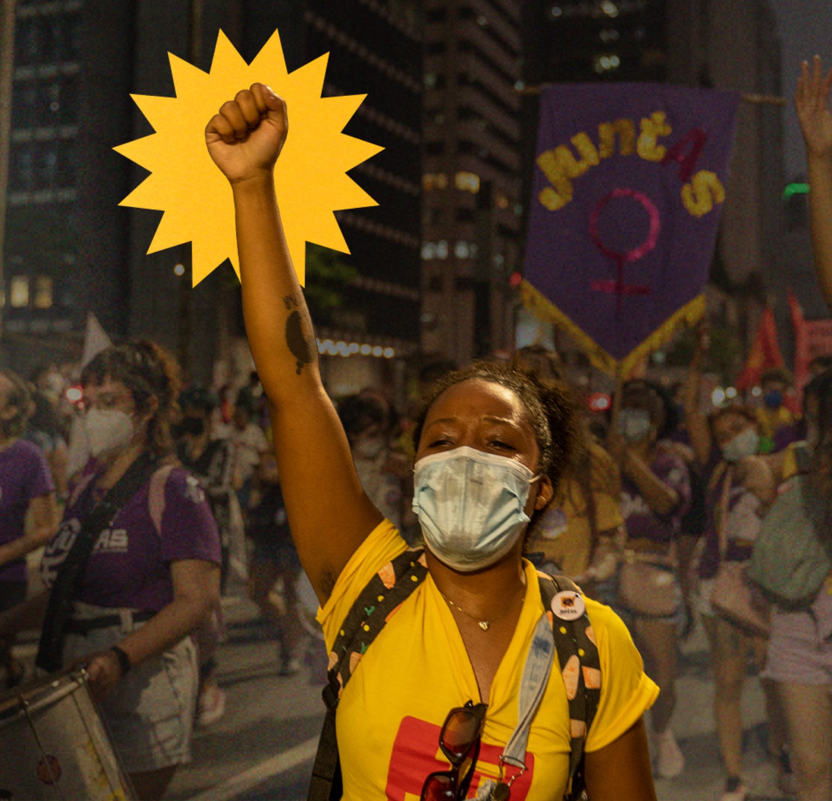 Mulher negra com punho levantado em meio à uma manifestação de rua